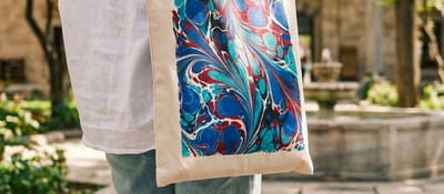 Woman carries a colourful marbled tote bag in a mosque courtyard, Ebru workshop in Istanbul.