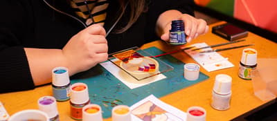 Woman paints a stained glass panel with vibrant colors at a workshop in Istanbul