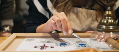 Hands arranging glass mosaic pieces to craft a Turkish lamp in Istanbul