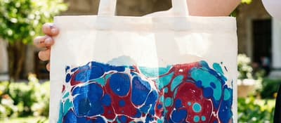 Holding a tote bag decorated with blue and red Ebru marbling at an Istanbul workshop