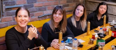 Four smiling women at a long table set for a Turkish coffee workshop in Istanbul