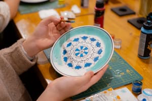 Holding a finished blue and white Turkish tile (çini) plate at an Istanbul ceramic painting workshop