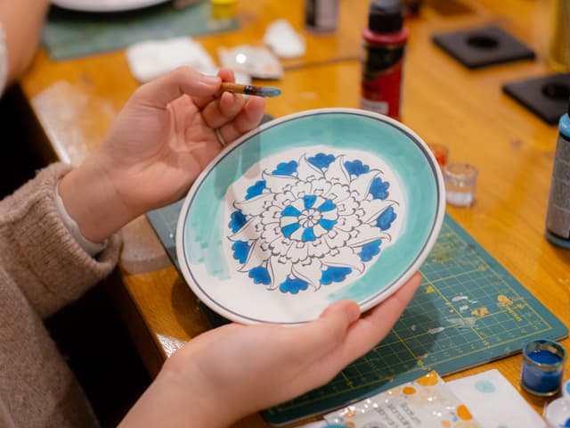 Holding a finished blue and white Turkish tile (çini) plate at an Istanbul ceramic painting workshop