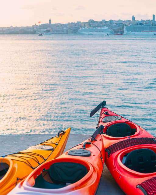 Gün batımında kıyıda duran kırmızı ve sarı deniz kanoları; İstanbul Boğaz'da kano turu.